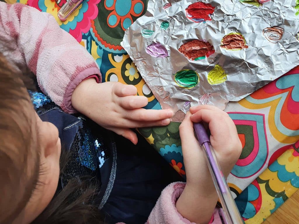Foil Zentangle Easter Eggs - a little girl drawing eggs with sharpie marker on foil.