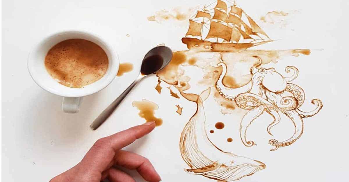 A coffee cup, a spoon and a hand pointing a finger at a drawing of a ship and a whale, painted with the coffee