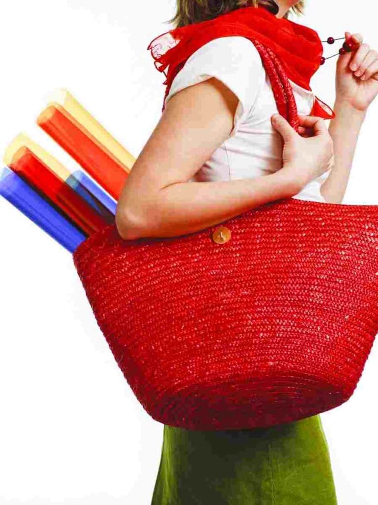 a woman carrying art supplies to class in a red bag