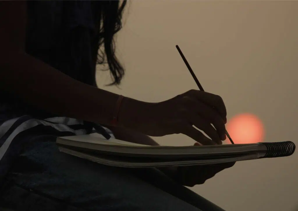 uma mulher desenhando contra um pôr do sol